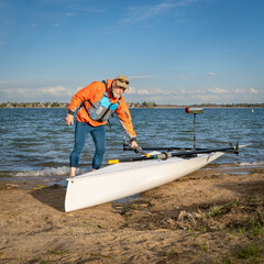 Senior male rower with his rowing shell on a beach of Boyd Lake in northern Colorado, serly spring scenery © MarekPhotoDesign.com