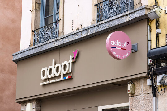 Macon, France - 01 August 2026: Storefront sign and round logo of Adopt Parfums Francais perfume shop on historical building wall.