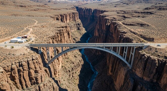 Modern arch bridge spanning a deep, vast canyon with a river below