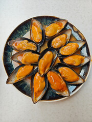 Steamed mussels on the half shell served with savory sauce on a ceramic plate © Monic249