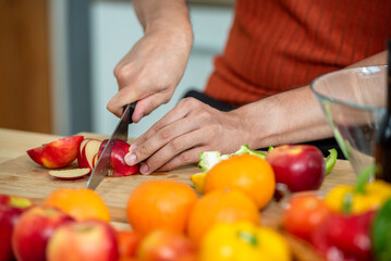 Naklejka premium Hand chef knife cut and slice fresh Vegetables baby cos salad on wood board table .Make Salad Organic Vegetables mix lunch with vegetables and fruit at kitchen table on wood cutting board.