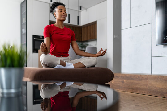 Meditation session at home with woman sitting cross-legged on modern couch