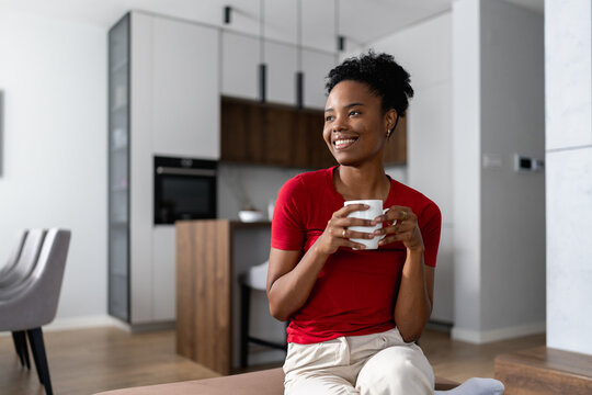Woman holding a cup of coffee in modern home during morning hours