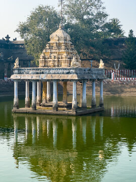 Stone pillared mandapam pavilion reflected in the calm temple tank at Varadharaja Perumal Temple, Kanchipuram, Tamil Nadu, India