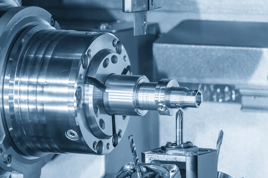 Mass production of high precision metal parts by multi-tasking CNC lathe machine in blue tone lighting