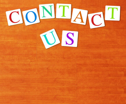 CONTACT US text made of colorful alphabet letters on wood background