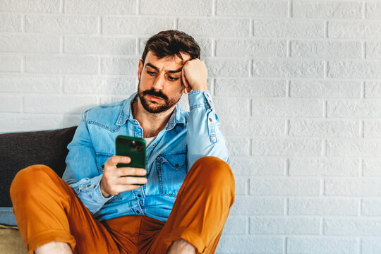 A disappointed man checking his smartphone, online problems, bad news, digital setbacks
