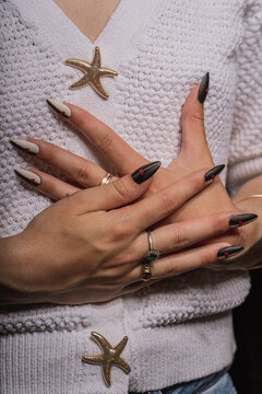 Woman Crossing Hands on Chest Displaying Elegant Black White and Gold Nail Art