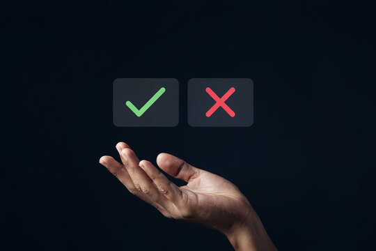Hand holding check mark and cross symbols on dark background, decision making.