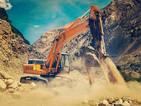 Vintage retro effect filtered hipster style view of excavator doing road construction in Himalayas. Ladakh, Jammu alongside Kashmir, India