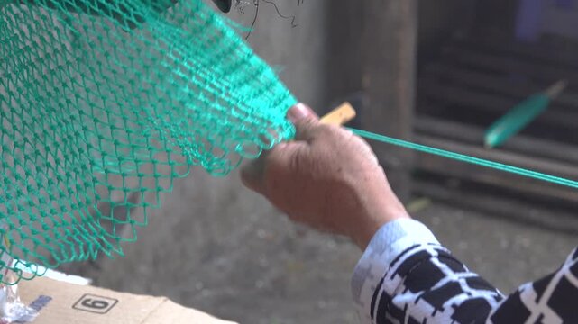 The Vietnamese handicraftsman weaves a net with the help of a special needle like a shuttle