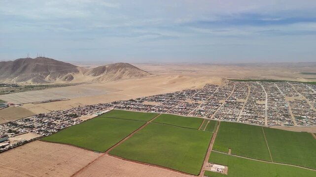Aerial drone view of a desert landscape with the Huacachina oasis, sand dunes and the city of Ica. Peru	