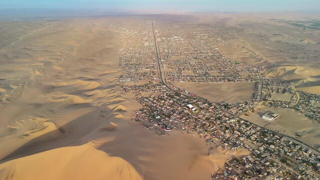 Aerial drone view of a desert landscape with the Huacachina oasis, sand dunes and the city of Ica. Peru	