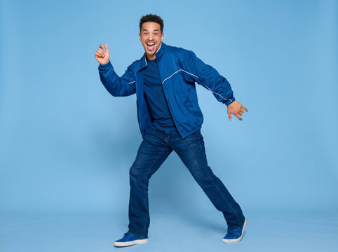 young man dancing on blue background.