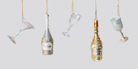 Fototapeta premium Minimal creative aesthetic banner of Glasses of wine and Champagne bottles, hanging Christmas ornaments. New Year bright glass toys. Festive minimal concept of celebration, party, winter holidays.