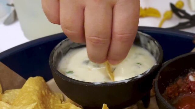 Dipping chips in a mexican queso cheese dip