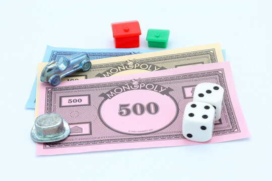 Monopoly game night concept. 500 monopole dollar cash banknotes currency.  Car, hat, green house, red hotel and double dice Close up photo.
