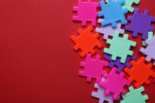 Children's plastic construction set, puzzles on red background. Teamwork, business concept