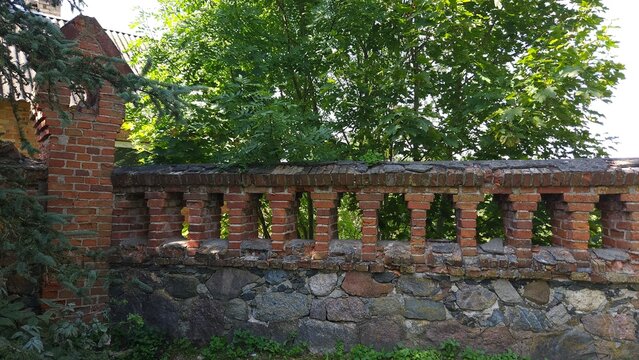 Brick wall fence with stone base and green foliage in background  