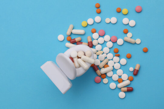 Miniature toy toilet and many pills on blue background