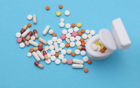 Miniature toy toilet and many pills on blue background