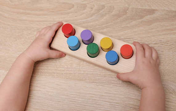 A toddler plays with a wooden color sorter. Develop toddler's logic and motor skills.