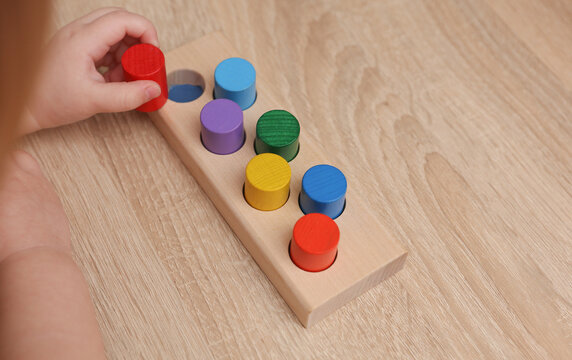 A toddler plays with a wooden color sorter. Develop toddler's logic and motor skills.