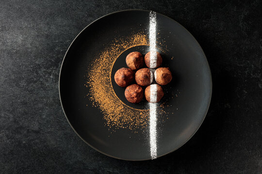 Chocolate truffles on a black plate.