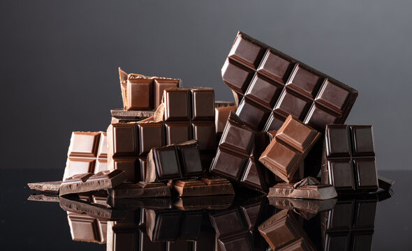 Broken bitter and milk chocolate bars on a black background.