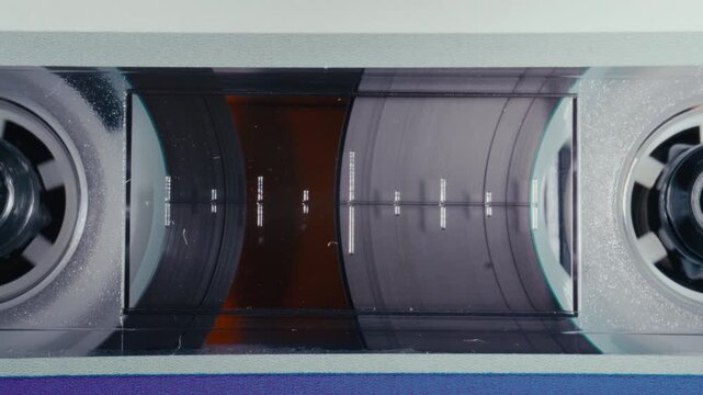 Retro audio cassette tape reels spinning magnetic ribbon smoothly during music playback. Extreme close-up view, no people