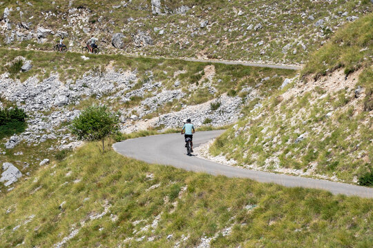 Cyclists Riding on Winding Mountain Road in Montenegro, Scenic Outdoor Cycling Adventure Through Rocky Highland Landscape