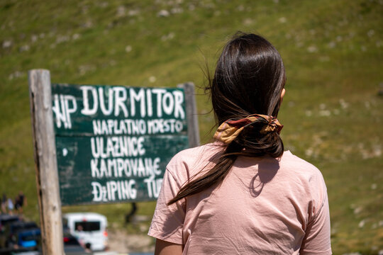 Female Tourist at Durmitor National Park Entrance Sign in Montenegro, Summer Mountain Travel and Outdoor Adventure