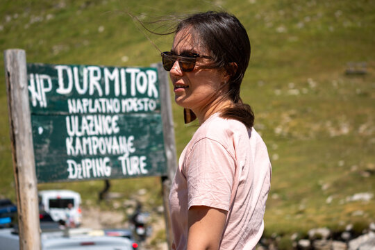 Female Tourist at Durmitor National Park Entrance Sign in Montenegro, Summer Mountain Travel and Outdoor Adventure