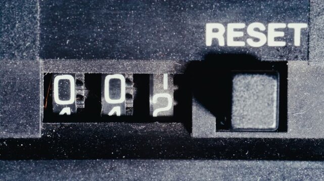 Three-digit vintage analog counter mechanism with last digits turning during music playback on retro cassette tape player. Macro close-up view