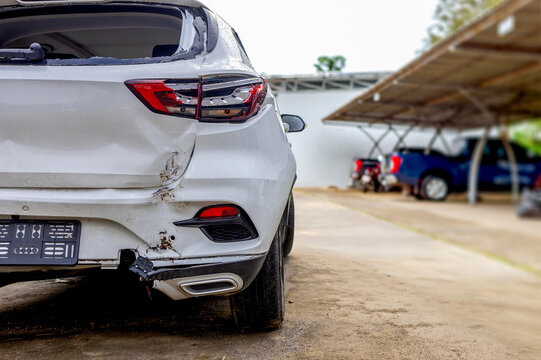 Damaged white car rear after traffic accident on urban street with copy space