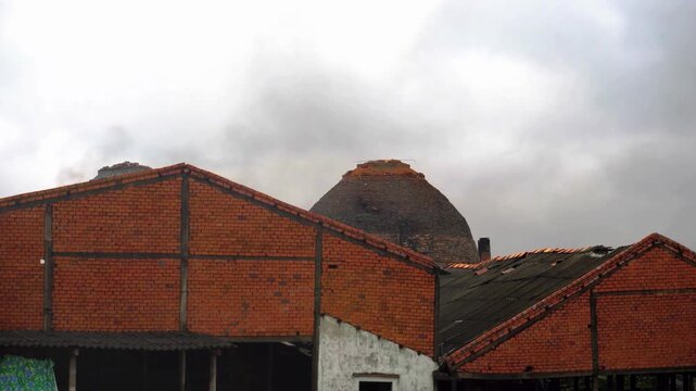 A mesmerizing time lapse of smoke billowing from traditional brick kilns and factories, creating a dramatic, cloudy atmosphere with industrial architecture.