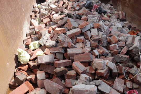 Close-up of pile of old bricks in a countainer with other garbage. Construction industry and garbage of bricks.