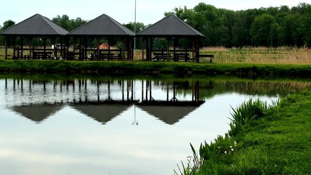 Wooden gazebo reflected in the calm water of a lake