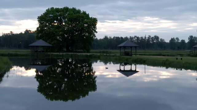 Wooden gazebo reflected in the calm water of a lake
