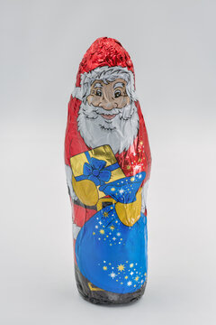 Chocolate Santa Claus wrapped in foil closeup on white.