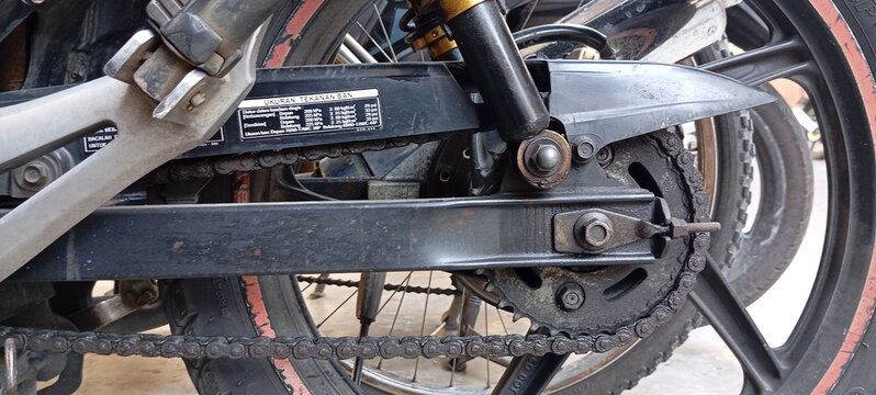 Horizontal Close-Up of a Dirty Motorcycle Drive Chain, Sprocket, and Swingarm