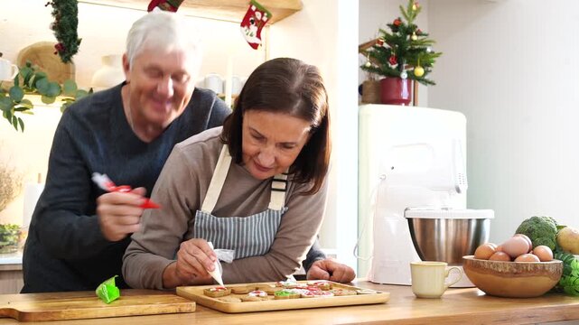 Grandpa and Grandma's family happily decorated gingerbread cookies together with cream cheese, preparing food for a Thanksgiving and Christmas party at home. 