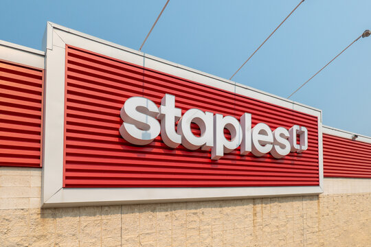 Calgary, AB, Canada. August 16, 2026. Low angle view of white Staples logo letters mounted on a red wall on a retail store facade.
