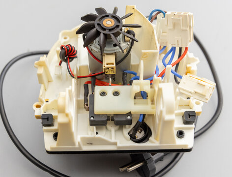 Disassembled electronic device showing motor, fan, switches, and electrical connections