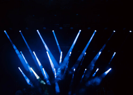 Concert stage view from performer perspective with blue spotlights and smoke
