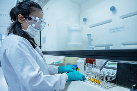 Female researcher handles toxic chemical samples inside a laboratory fume hood. Concept of chemical safety, hazardous substances, toxicology, scientific research, and exposure prevention.