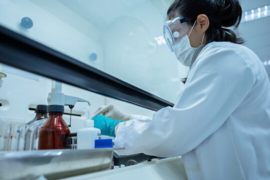 Female researcher handles toxic chemical samples inside a laboratory fume hood. Concept of chemical safety, hazardous substances, toxicology, scientific research, and exposure prevention.