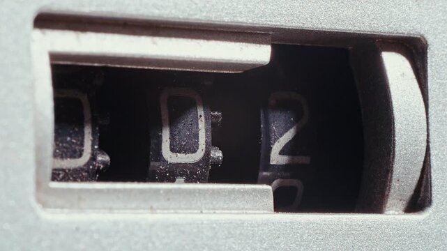 Three-digit mechanical analog tape counter with spinning number wheel on vintage cassette player deck. Extreme close-up view