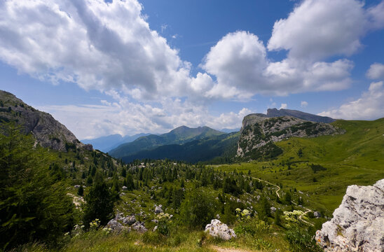 serene mountain landscape with trees and rocks in alpine valley from high vantage point. nature's majesty captured in vivid green and blue hues. adventure and travel inspiration.
