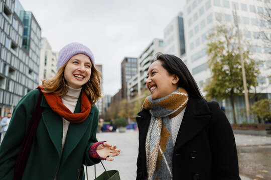 Happy women friends talking in urban cityscape